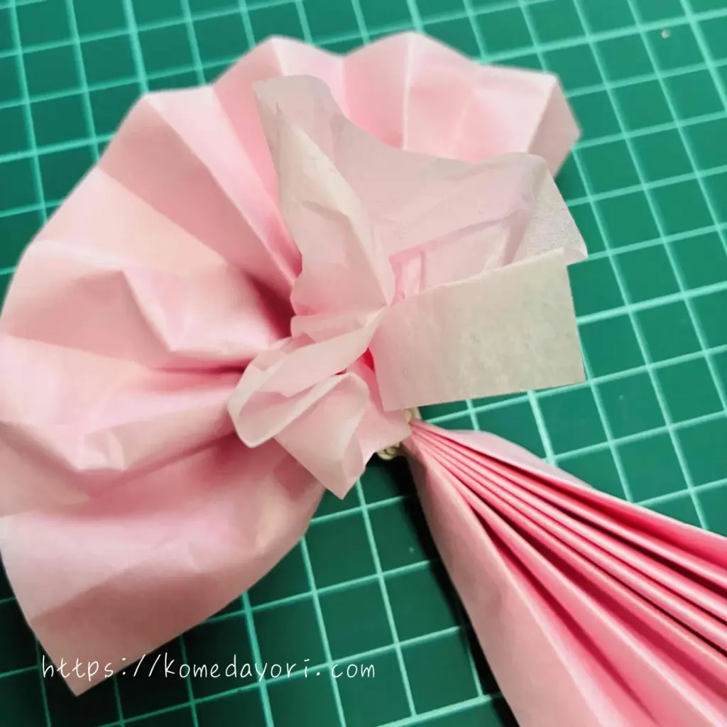 蛇腹折りしたフラワーペーパーを１枚ずつ引き上げ広げていく画像