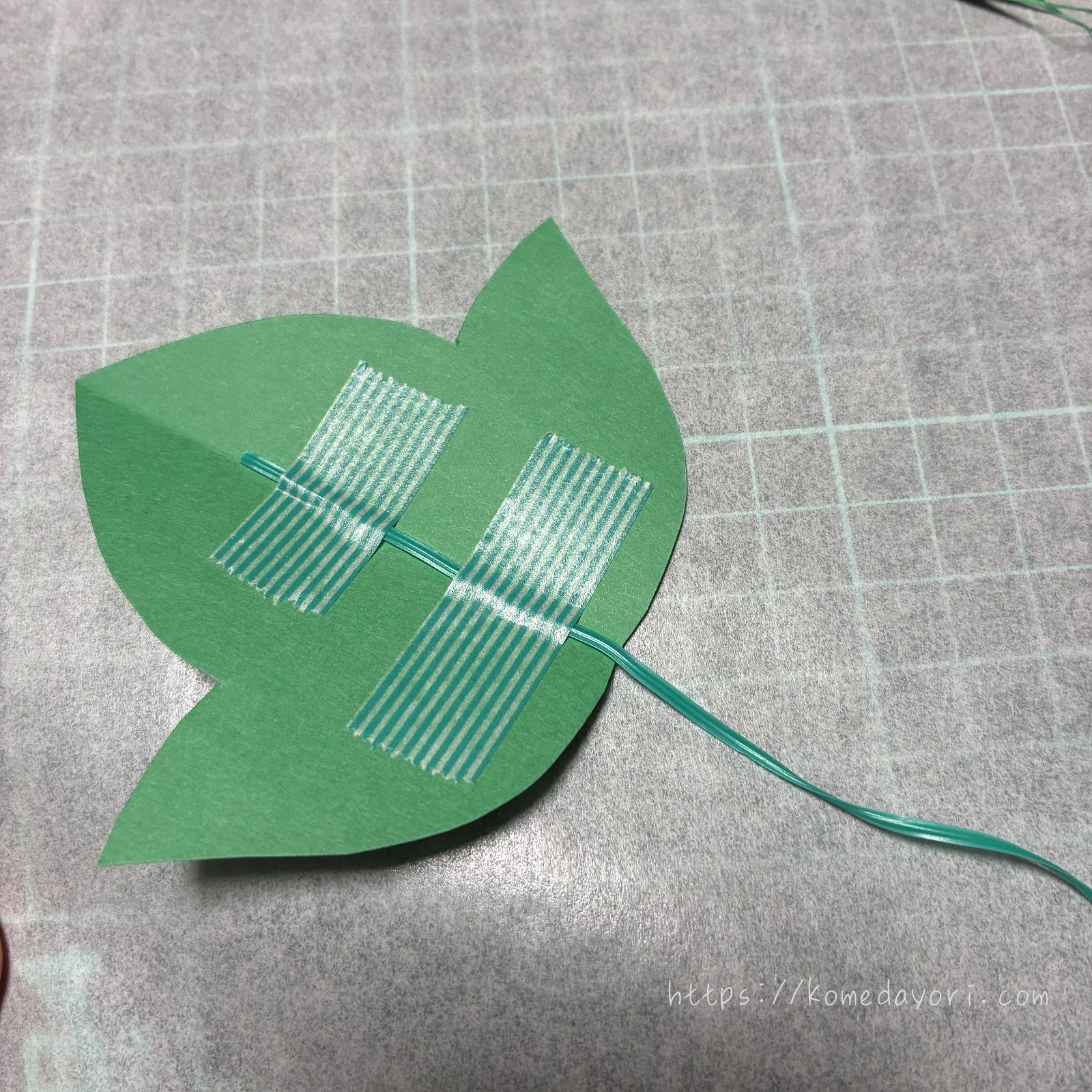 葉型に切った画用紙の裏に園芸用のタイをテープで貼り付けている工程画像