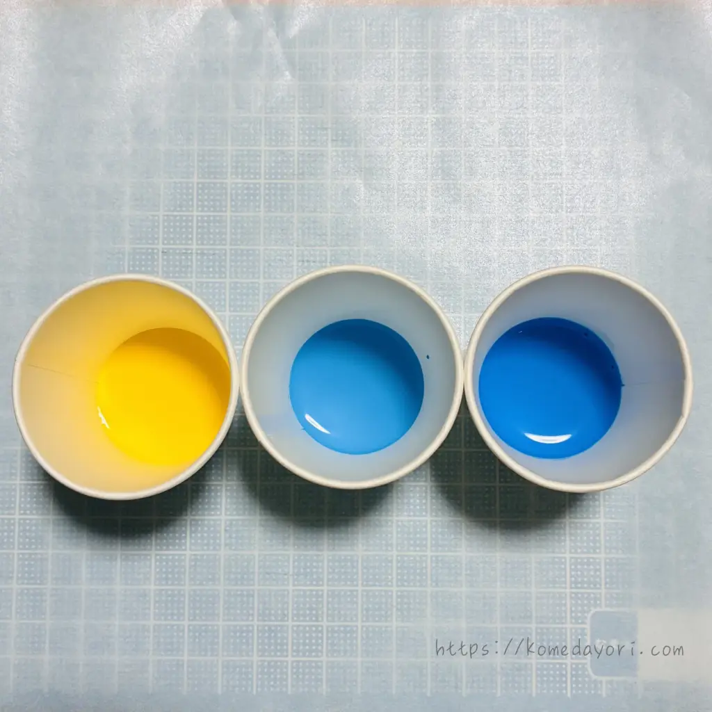 紙コップに入った水で溶いた絵の具。黄色、水色、青の順で並んでいる。