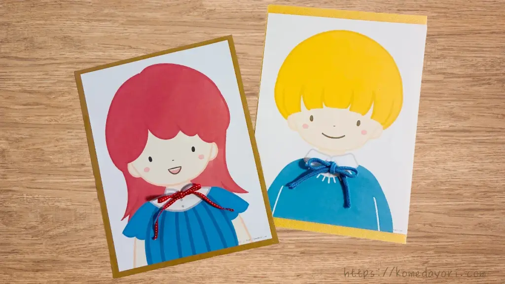 ひも結び練習ボードの完成品画像。用紙に印刷された男の子と女の子の胸元にちょうちょ結びのリボンがついている