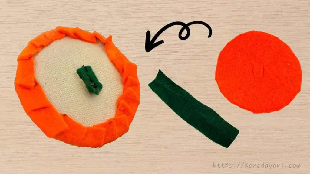 切り取った紙ボウルの底にオレンジの円フェルトと緑のフェルトを組み合わせて、カボチャのフタとヘタを作る工程