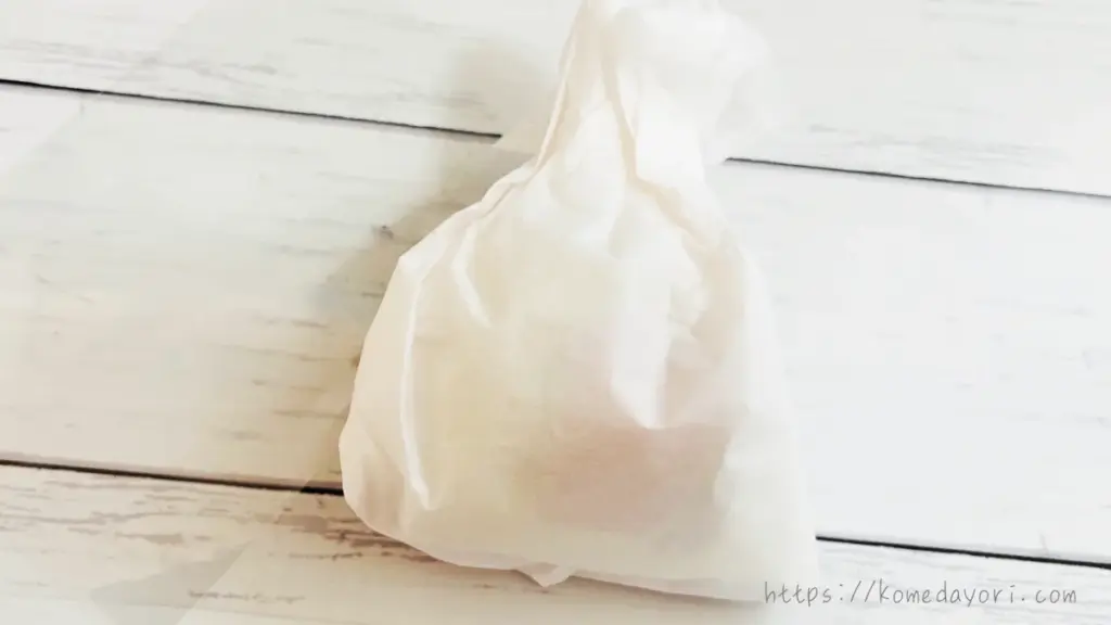 白いフラワーペーパーでお菓子を包み、巾着型にしたラッピングの途中段階。