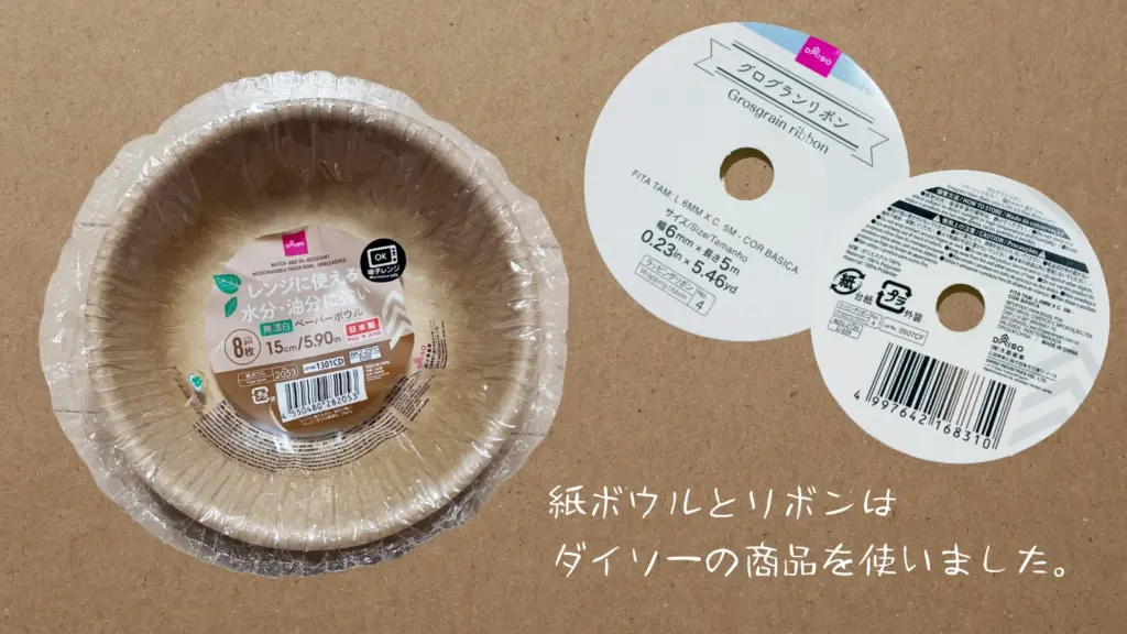 工作で使った材料の一部。ダイソーで購入した紙ボウルとリボンのパッケージを並べている写真。「紙ボウルとリボンはダイソーの商品を使いました」と書かれている。