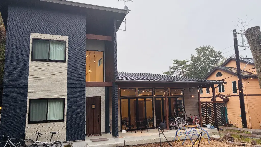 トロールの森ステラ別館の外観。大きな窓と黒×ベージュの外壁、ウッドのドア、屋根付きのテラスが写っている。