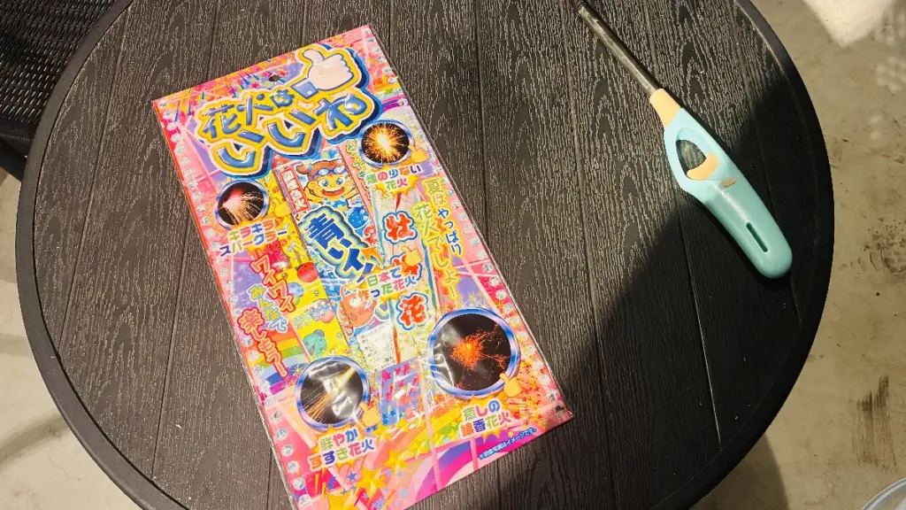 テーブルの上に置かれた250円で購入した手持ち花火セットとチャッカマンの写真。