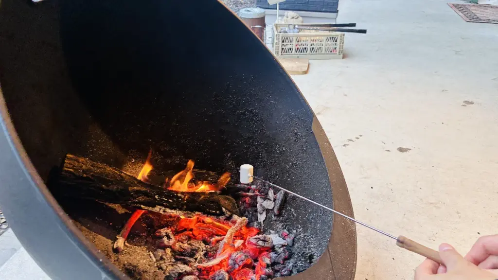 屋外の焚き火でマシュマロを焼いている様子。マシュマロを持つ手が写っている。