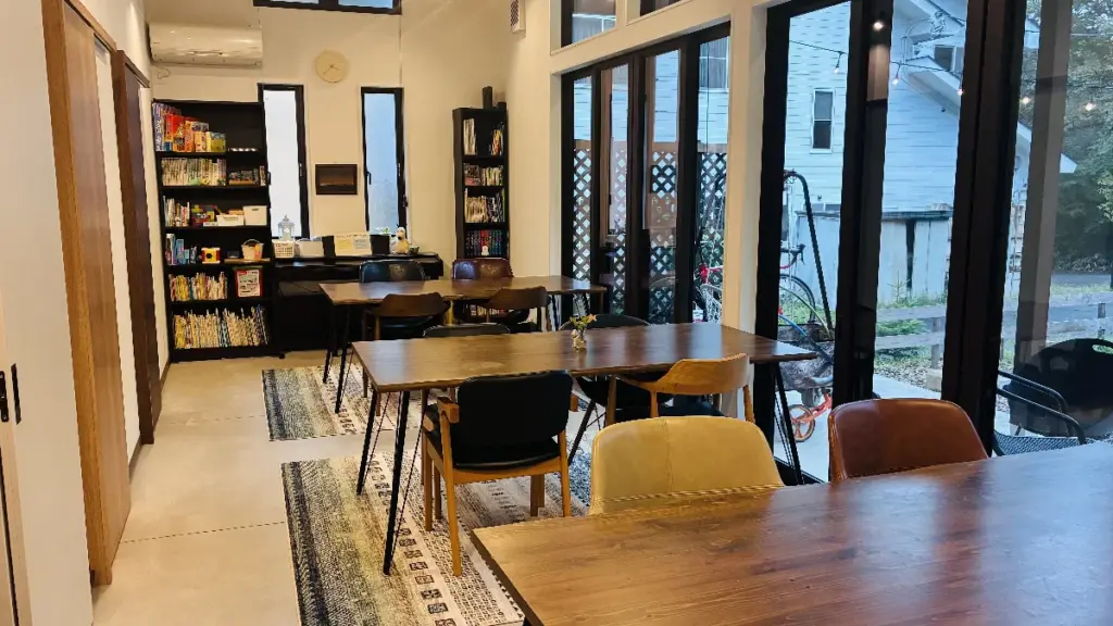 トロールの森ステラのダイニングルーム。大きな窓と木製テーブル、本棚に並ぶ絵本やボードゲームが写っている。