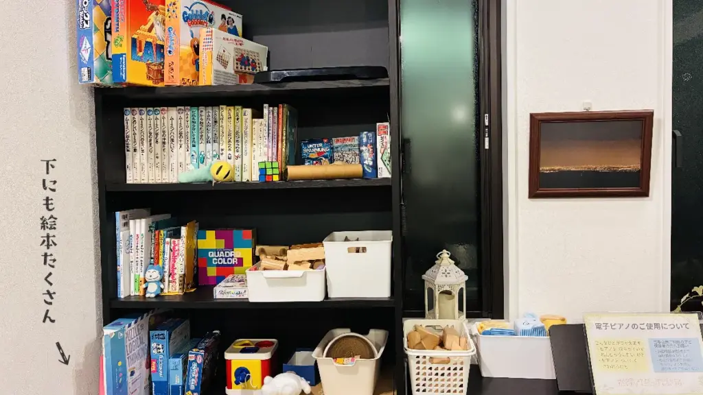 共有スペースにある絵本やボードゲーム、おもちゃが並ぶ棚の写真。