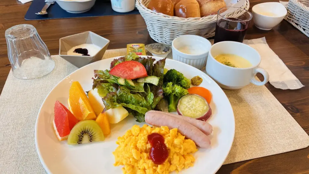 トロールの森ステラの朝食プレート。スクランブルエッグ、ウインナー、サラダ、さつまいも、フルーツの盛り合わせに、スープやヨーグルト、パンが並んでいる。