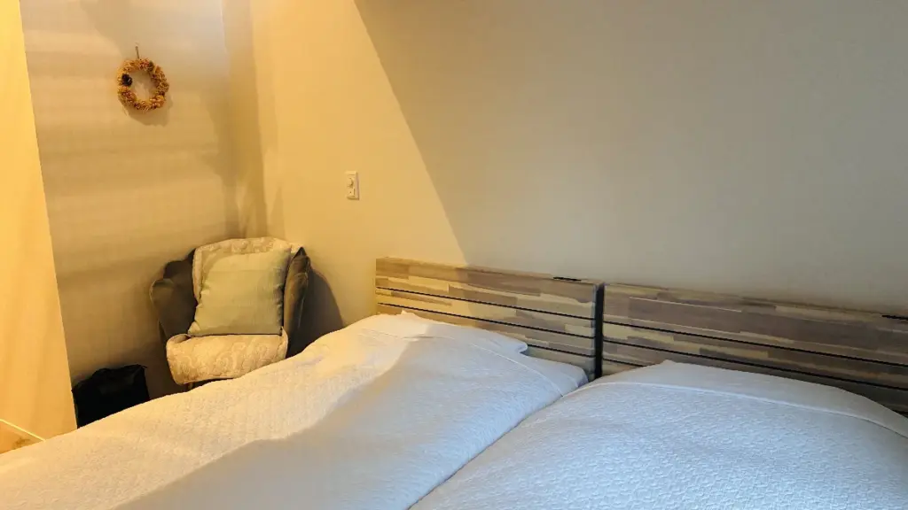 トロールの森ステラの客室のベッドとクッションが置かれた椅子の写真。