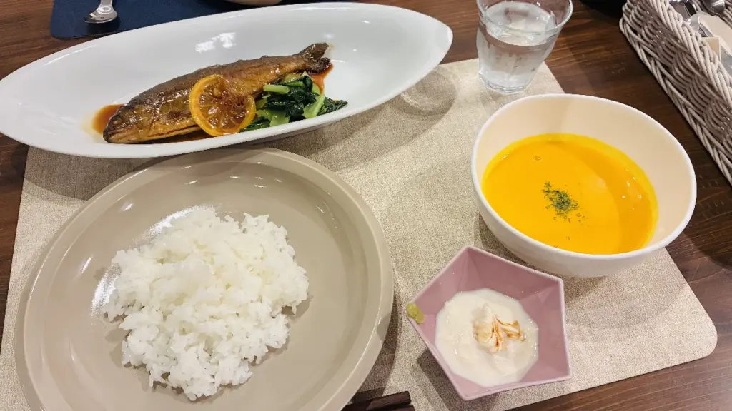 トロールの森ステラの夕食。煮付けの魚料理、かぼちゃスープ、ご飯、小鉢のセットがテーブルに並んでいる。