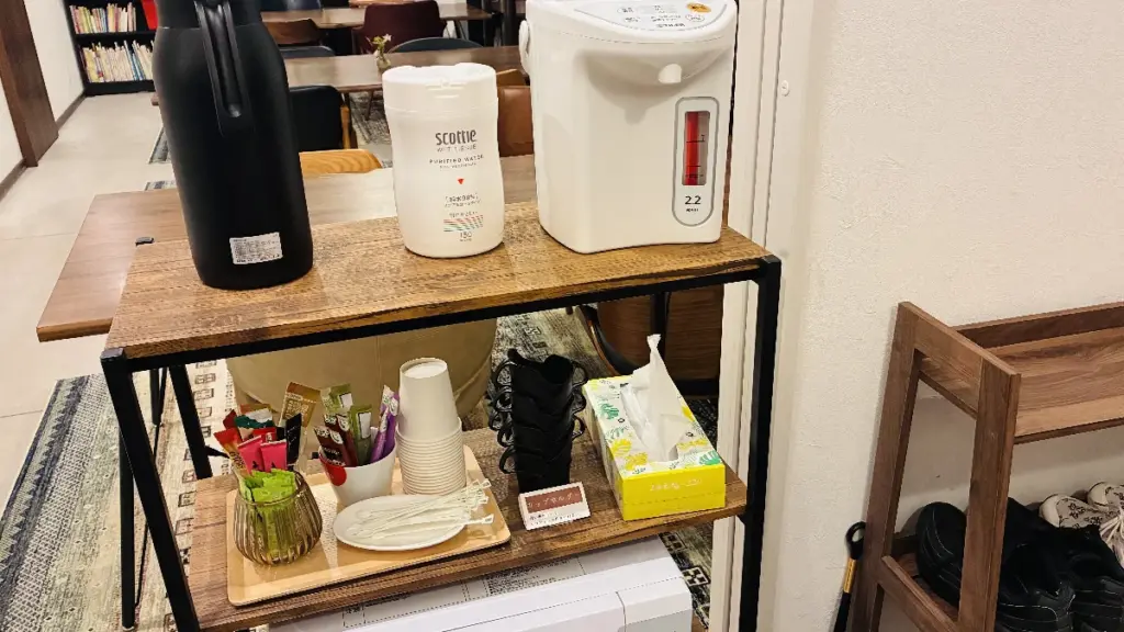 共有スペースに設置されたフリードリンクコーナー。電気ポット、紙コップ、インスタント飲料、ティッシュなどが並んでいる。