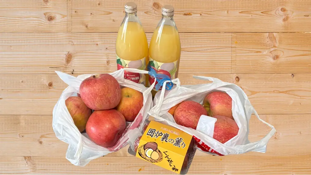 荒巻りんご園で購入・収穫したりんご、りんごジュース、くんせい卵を並べた写真。