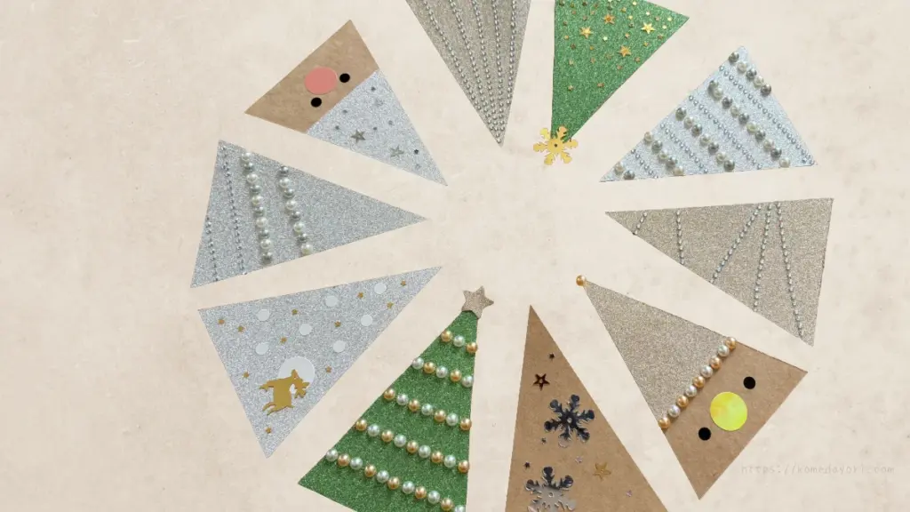 さまざまなデコレーションを施したクリスマスツリー型カードの完成例。円形に配置された10枚のカードには、パール調シール、ドットシール、ラメペン、星のシール、雪の結晶など、それぞれ異なるデコレーションが施されている。