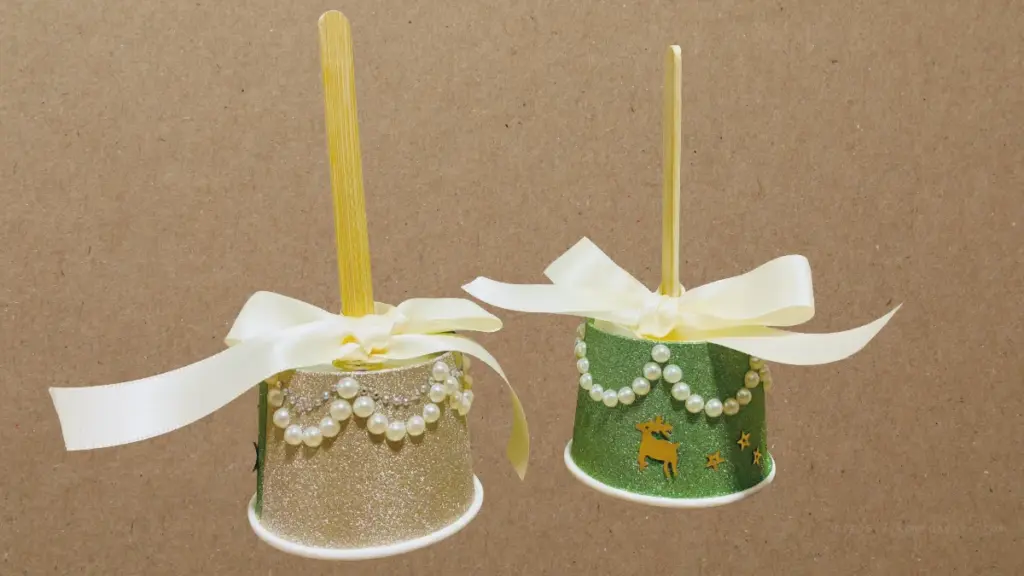 完成したハンドベル2個の全体像。ゴールドとグリーンのグリッターカップに白いリボン、パール調シールで装飾されている。