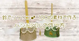 鈴でリンリン♪100均素材で作るハンドベルの作り方。完成したハンドベル2個（ゴールドとグリーン）を白い木目調の背景に配置。雪が降るような演出で冬らしい雰囲気。タイトル文字入りアイキャッチ画像。