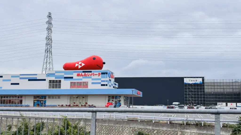 道路から見えるめんたいパーク群馬の外観。屋上に大きなタラピヨのオブジェが乗った特徴的な建物