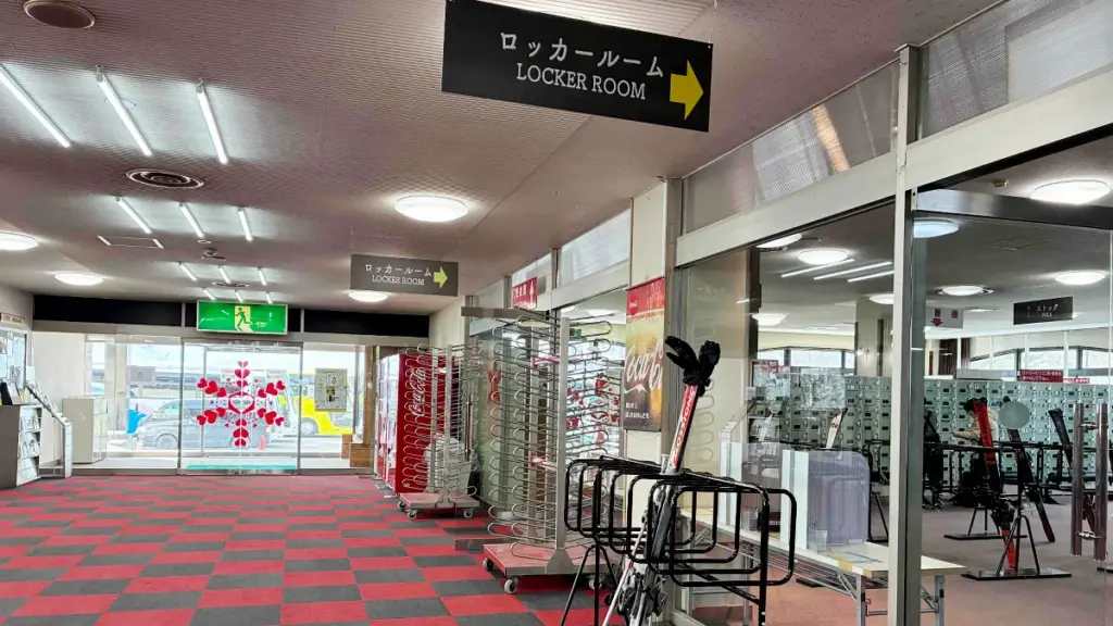 エーデルワイススキーリゾートのセンターハウス内。ロッカー室への案内看板と、整理されたレンタルスキー用具置き場。