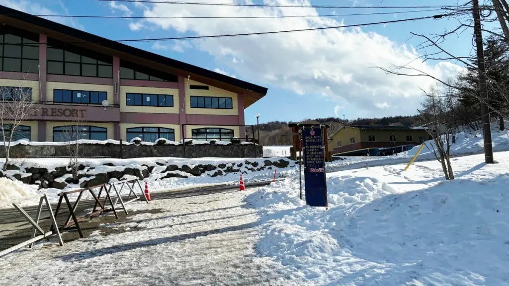 エーデルワイススキーリゾートのセンターハウス外観。雪が残る路面と、青空の下に広がるスキー場の建物。