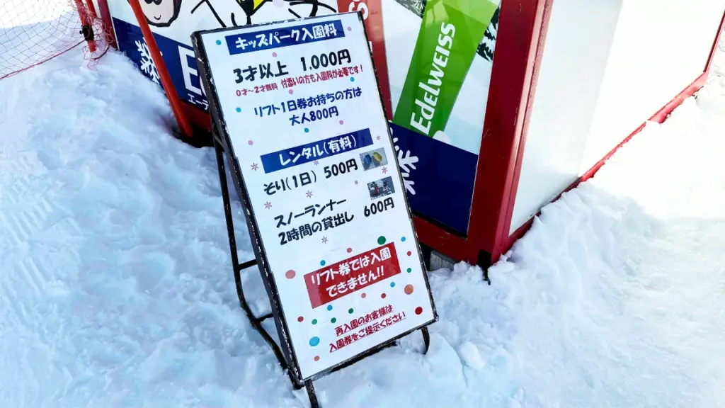 キッズパークの料金案内看板。3歳以上1,000円、ソリレンタル500円などの詳細が書かれている。