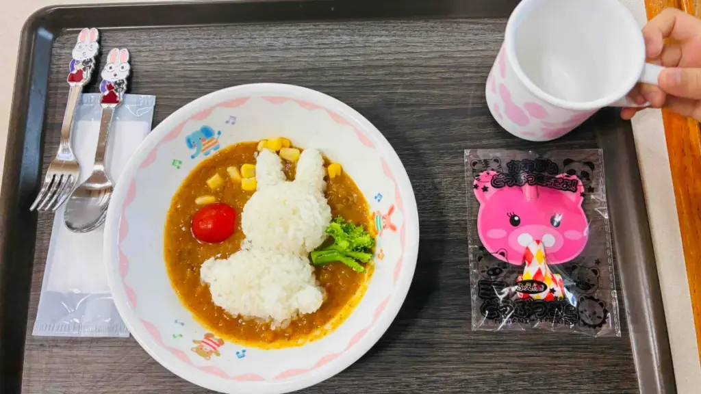ウサギの形に盛り付けたご飯のキッズカレー。ブロッコリーやミニトマトが添えられ、フォークとスプーンがセットされている。