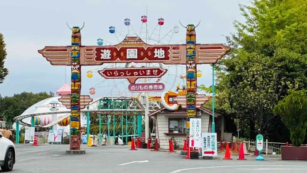 群馬サファリパークの遊園地エリア入口。トーテムポール風のゲートに「遊園地」と書かれ、奥に観覧車やアトラクションが見える。
