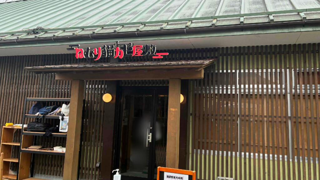 おさるランド「ねむり猫カピ屋敷」の看板が掲げられた、和風建築の建物の入り口。