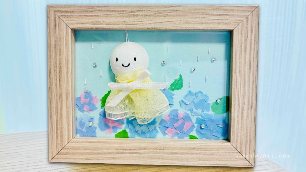 ダイソーの写真立てに飾った立体てるてる坊主と紫陽花の梅雨アート作品を机に置いた写真